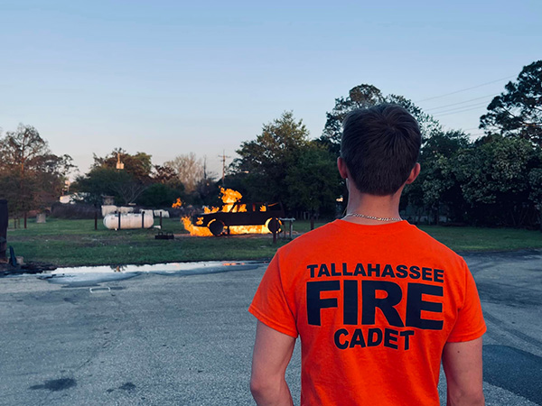 Back of a cadet watchin a fire burn